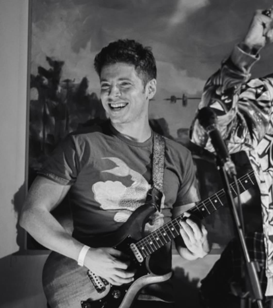 Julian Goddard laughing on stage mid-set, in black and white